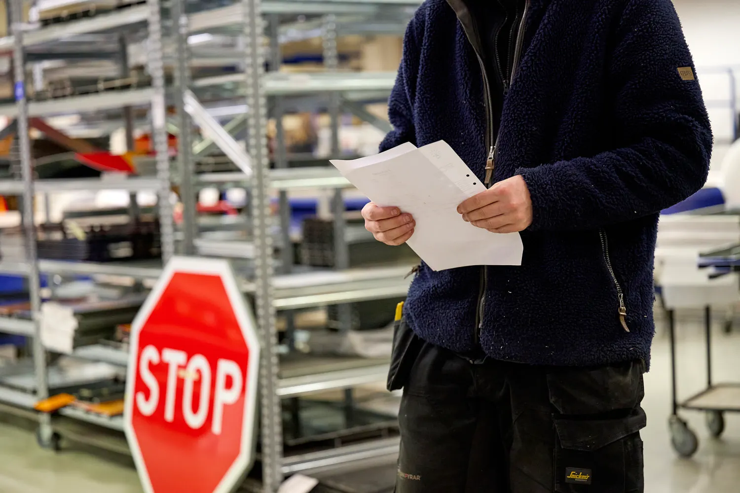Lagermedarbetare plockar en order bredvid ett stopplikt-märke i centrallagret