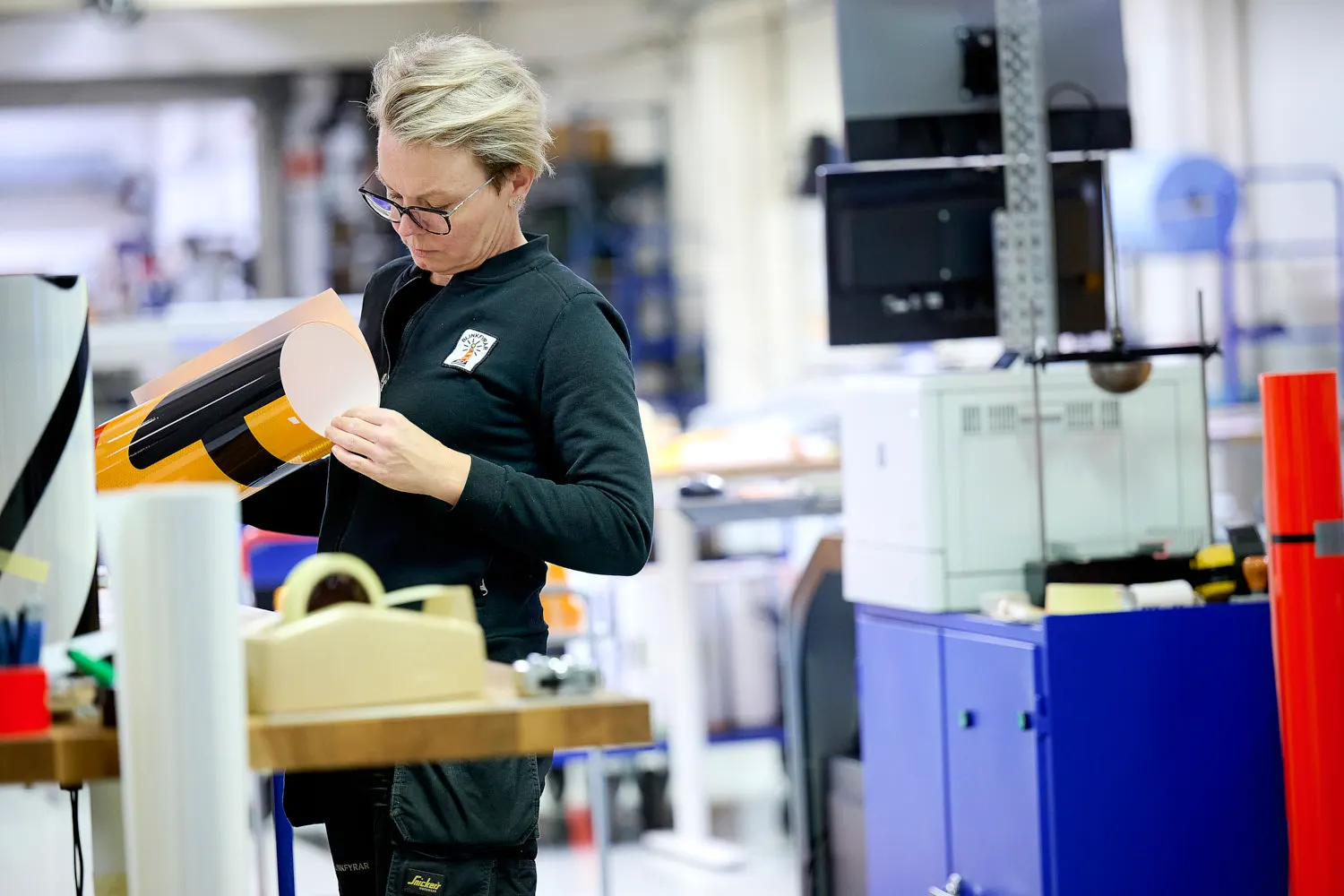 Medarbetare på Blinkfyrar applicerar reflexfolie på ett vägmärke i produktionen i Staffanstorp