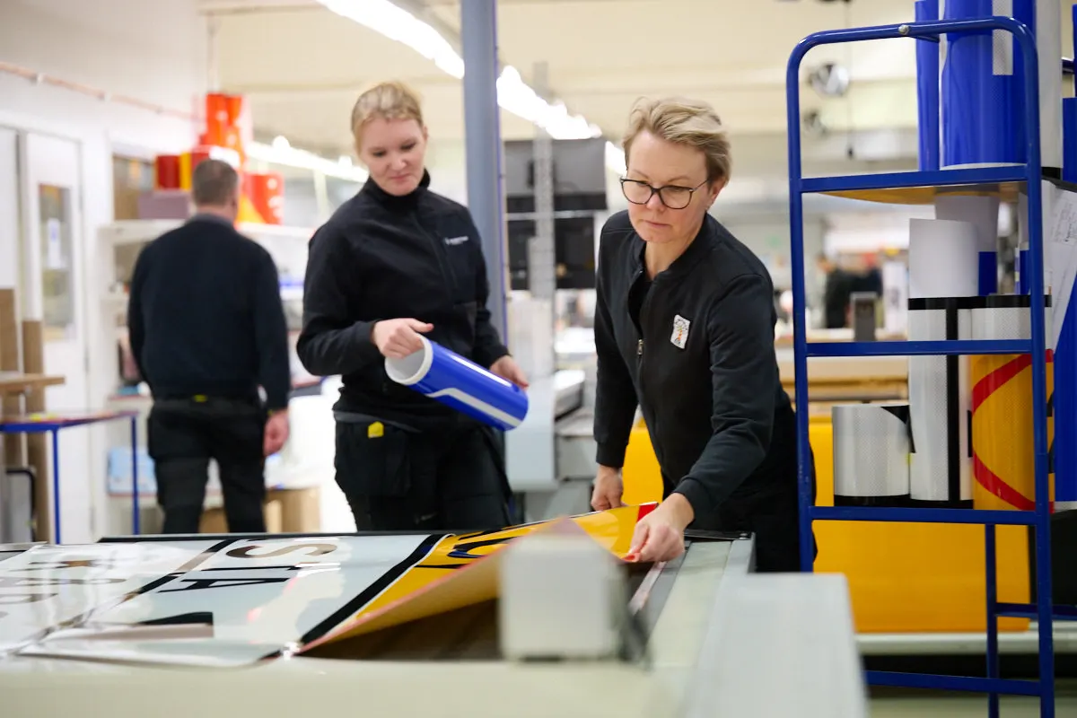 Medarbetare på Blinkfyrar arbetar tillsammans med skylttillverkning i produktionen